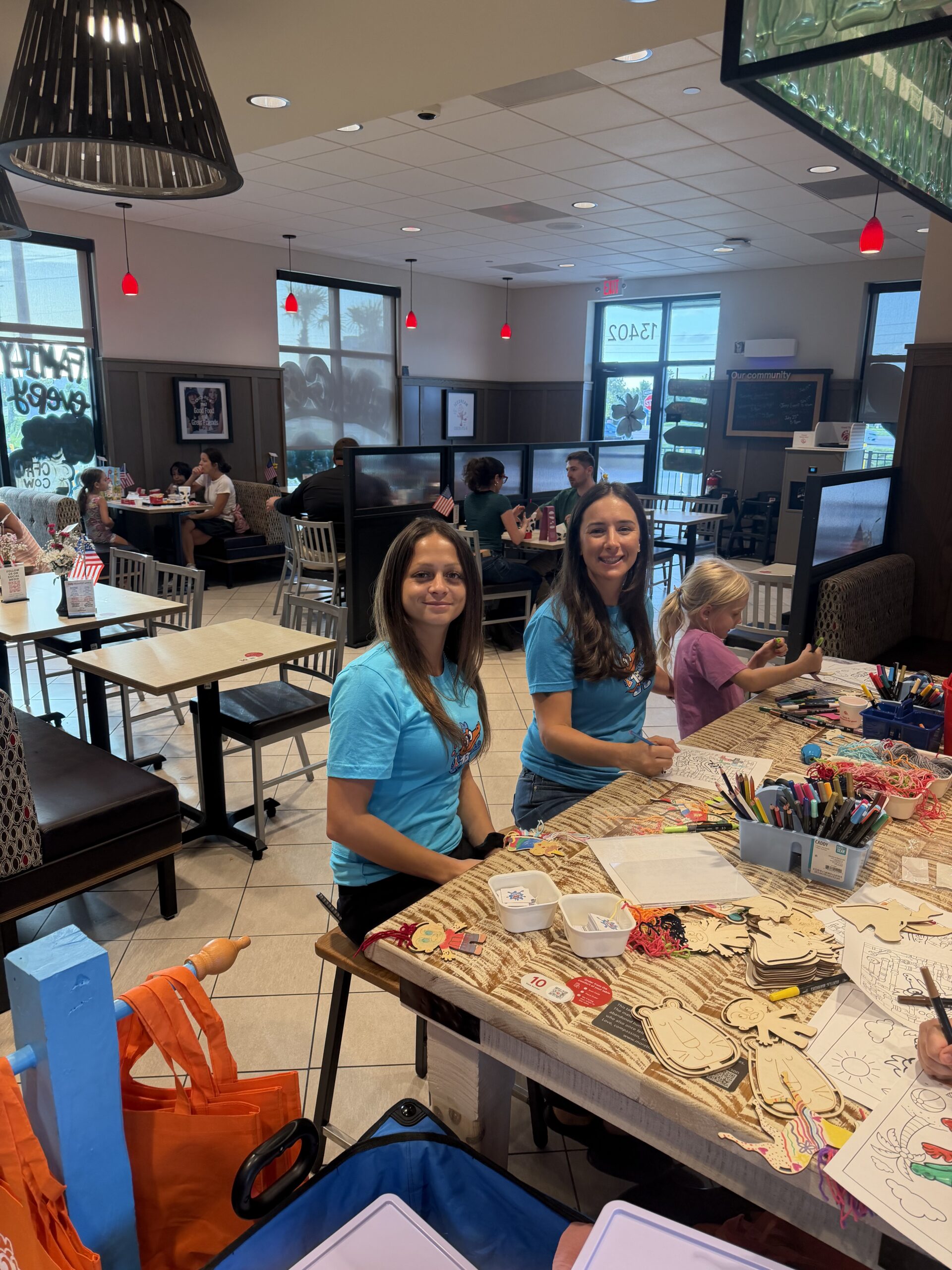 Two Formula Plumbing team members in branded shirts coloring at a kids craft table during a community event