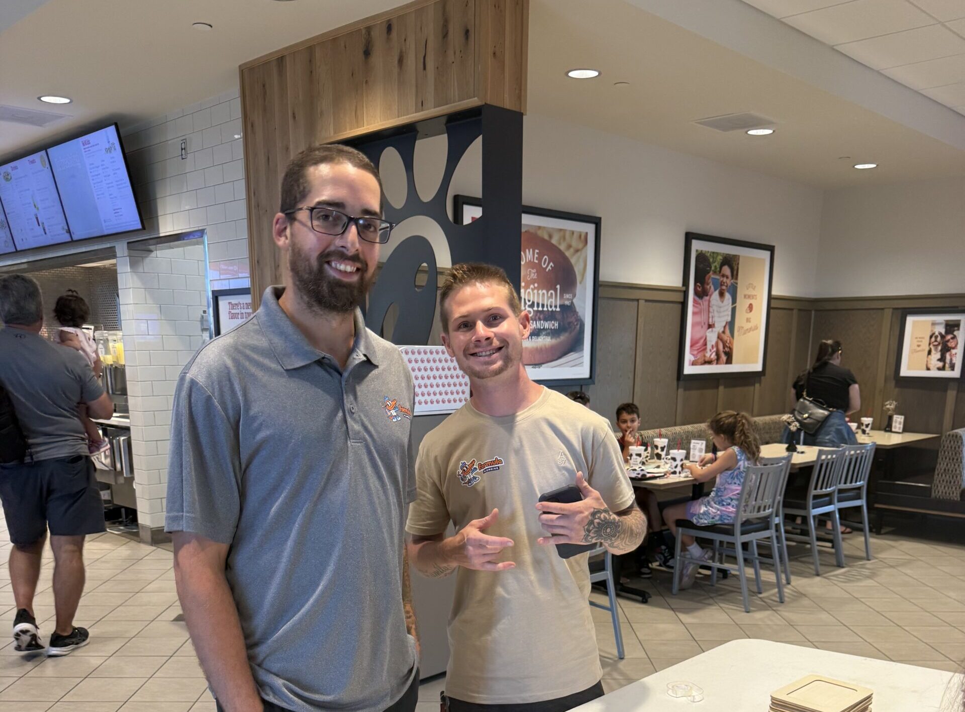 Two Formula Plumbing team members standing at a craft table set up for a kids event inside a restaurant