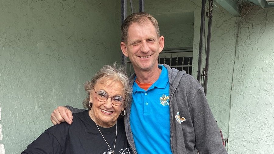 Joe, owner of Formula Plumbing, with a smiling customer outside her home after a plumbing job